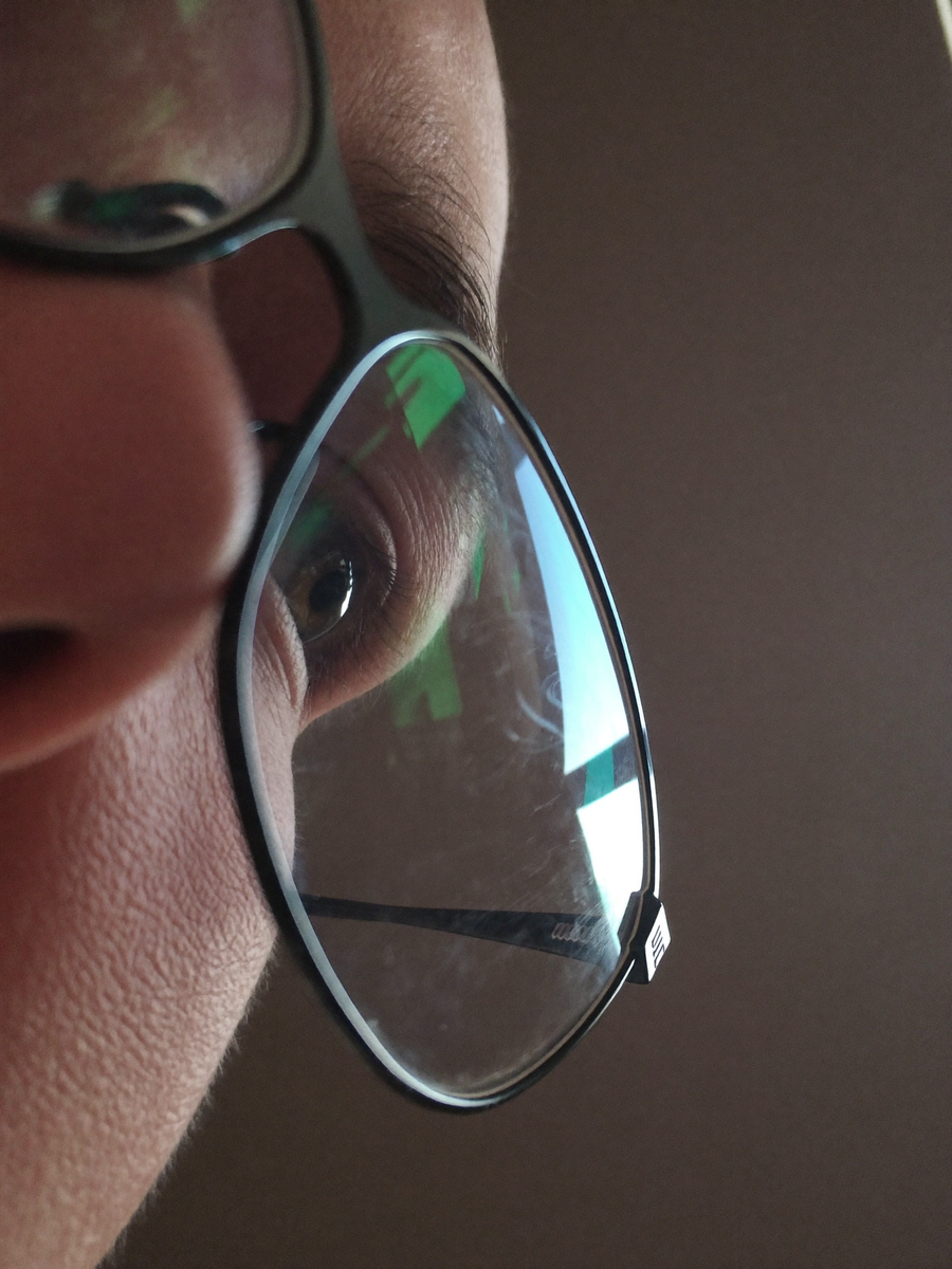 Close-up of an eye behind a lens with a screen reflected in it