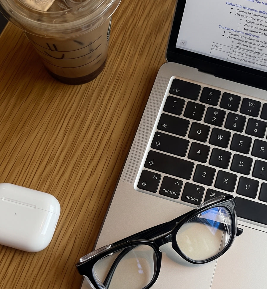 Adapt Dew glasses resting on a laptop keyboard beside an iced coffee, ready for a work session
