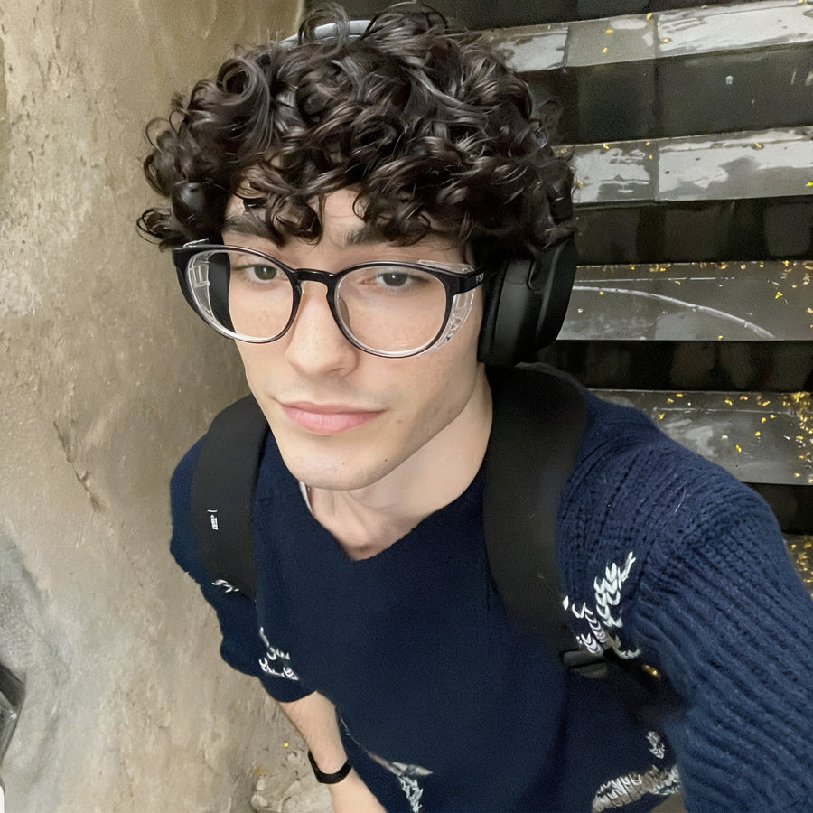 Man wearing Adapt Dew glasses and headphones outdoors on stairs