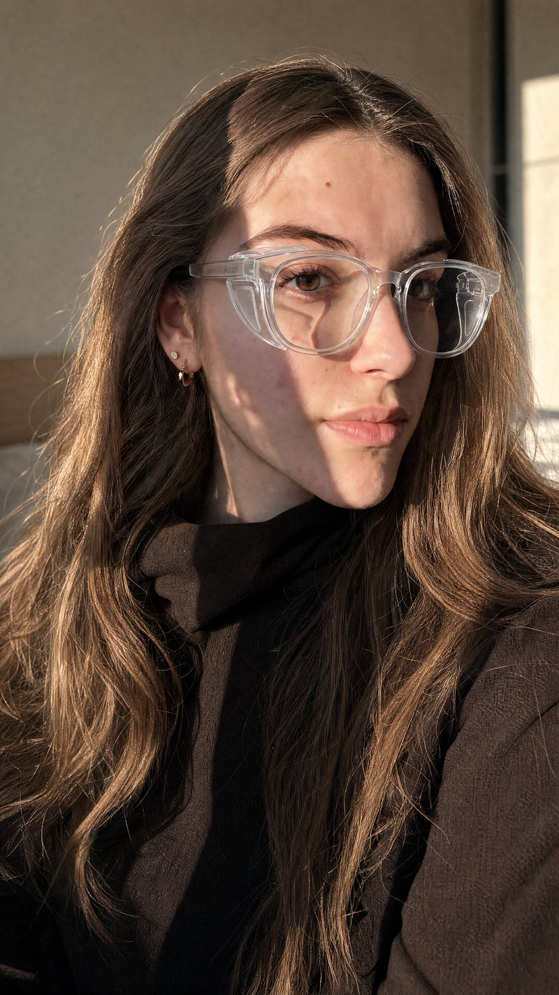 Woman wearing Adapt Dew clear glasses in warm natural light, homepage hero banner